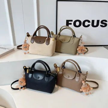 Several small handbags in black, cream and brown on a table, two with plush charms attached.