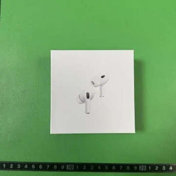 A white box of wireless earbuds placed on a green cutting mat.
