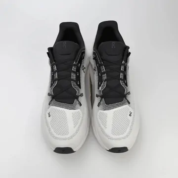 A pair of black and white running shoes photographed from above on a grey surface.